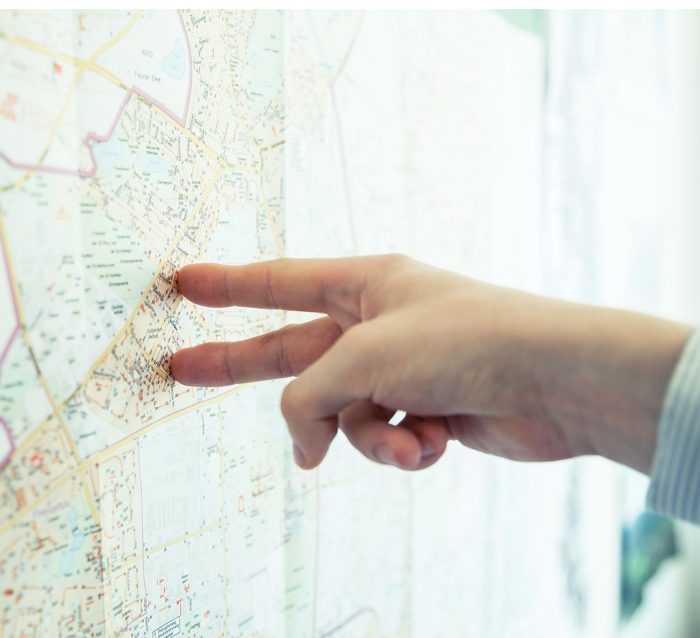Hand zeigt auf einen Stadtplan an der Wand