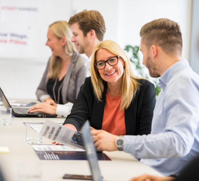 Team von Stadt + Handel bei einer Besprechung mit Laptops und Unterlagen