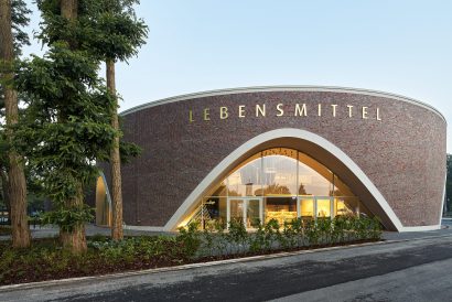 Runder Klinkerbau mit Schriftzug Lebensmittel und beleuchteter Glasfront in Oldenburg-Kreyenbrück