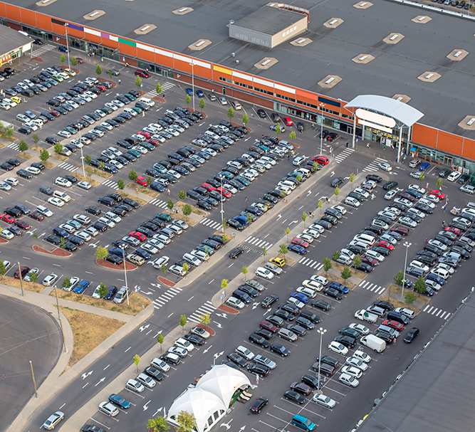 Luftaufnahme eines großen Parkplatzes vor einem Einkaufszentrum