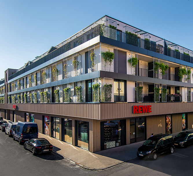 Wohn- und Geschäftshaus Ulanenpark mit REWE Markt im Erdgeschoss und begrünten Wohnetagen