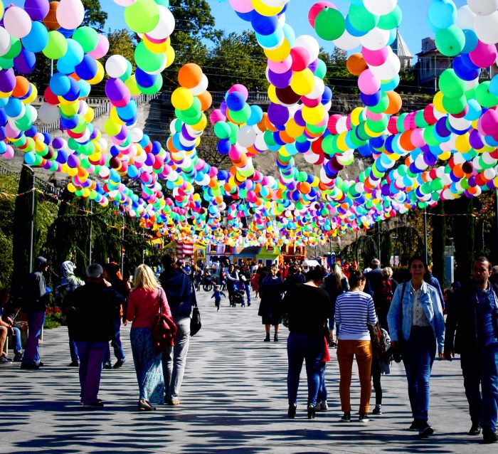 Promenade mit bunten Luftballongirlanden und vielen Spaziergängern an einem sonnigen Tag