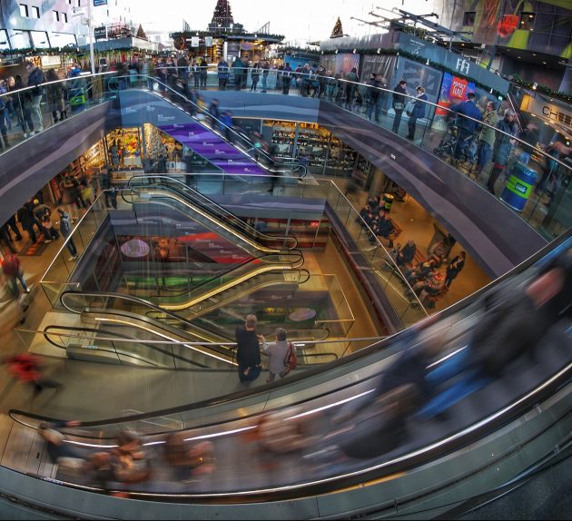 Blick von oben auf Rolltreppen und viele Besucher in einer mehrstöckigen Markthalle
