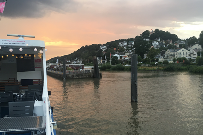 Blick vom Schiff auf den Anleger und die Hanghäuser von Hamburg-Blankenese im Abendlicht