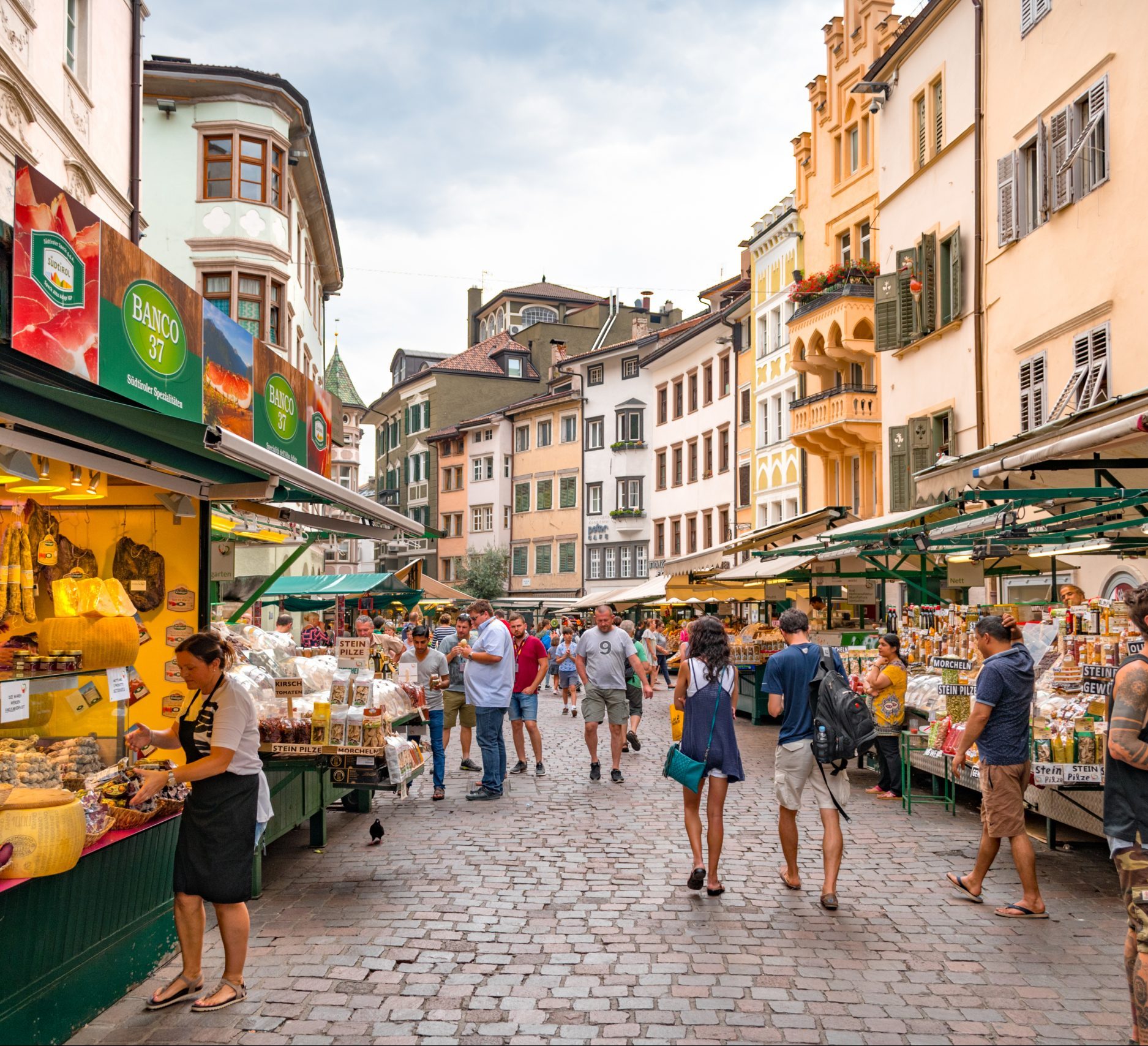 Markttreiben auf der Piazza delle Erbe in Bozen mit Ständen vor historischen Häusern