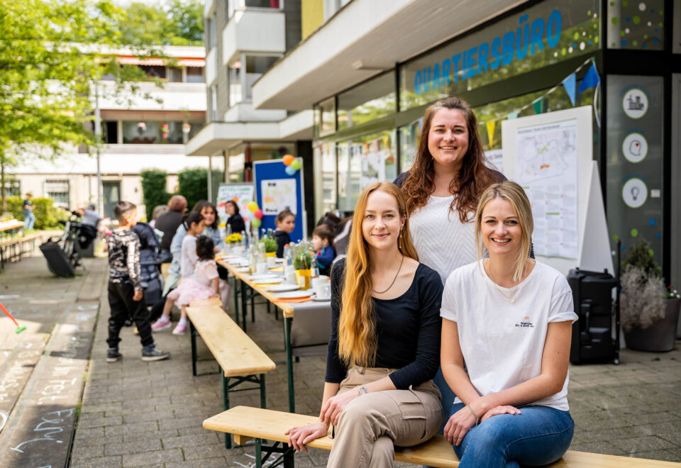 Team vor dem Quartiersbüro bei einer Vor-Ort-Aktion in Sandheide mit Bierbänken und Infotafeln
